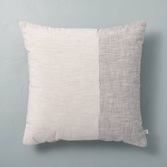 a white and grey pillow sitting on top of a gray wall