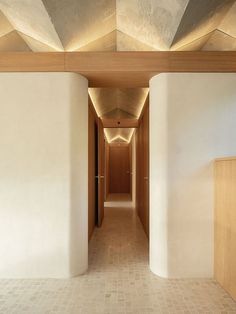 an empty hallway with white walls and wooden ceiling