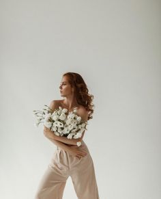 a woman with flowers in her hair is posing for a photo on the white background