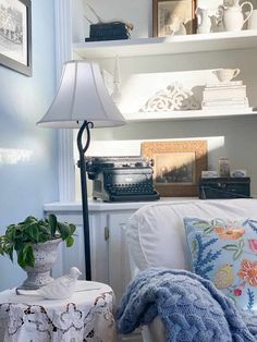 a white couch sitting under a lamp next to a table with a potted plant on it