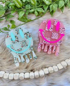 two pink and blue hand shaped brooches sitting on top of a fur rug