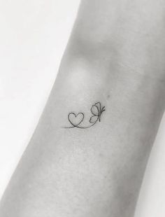 a small heart tattoo on the wrist with an arrow and two hearts attached to it