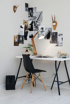 a white desk topped with a laptop computer next to a lamp and pictures on the wall