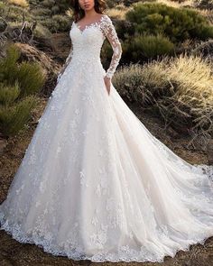 a woman in a wedding dress standing on a dirt road