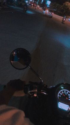 a person riding a motorcycle down a street at night with the lights on and speedometer showing