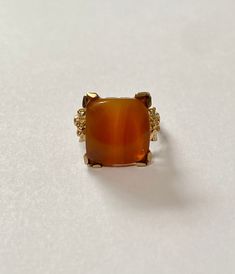 Vintage 10k yellow gold ring featuring a sizable agate stone. The cabochon boasts marbled orange brown, & beige earth tone colors. The gem is square cabochon cut & secured with decorative prongs. The setting is adorned with intricate pretty flower & leaf motifs. Stunning statement piece of fine vintage jewelry circa 1930! ERA - Circa 1930, Art Deco Era METAL / MATERIAL - 10k yellow gold, agate gemstone MARKINGS / HISTORY - 10k CONDITION - Excellent antique condition. Gem is securely Formal Yellow Gold Agate Rings, Gold Agate Cabochon Rings, Formal Amber Agate Jewelry, Elegant Brown Rings With Natural Stones, Formal Brown Cabochon Rings, Elegant Agate Rings For Collectors, 1930 Art, Brown Gemstone, Moss Agate Ring