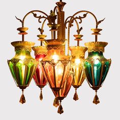 a chandelier with five lights hanging from it's sides and an ornate design on the bottom