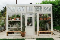 a white greenhouse with potted plants in it