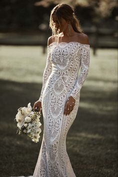 a woman in a white wedding dress holding a bouquet and looking off to the side