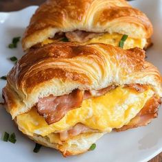 two croissants with meat and cheese are on a white plate next to each other