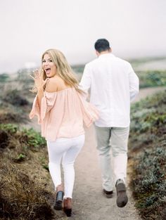 a man and woman walking down a dirt path