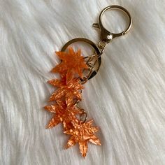 an orange maple leaf keychain hanging on a white fur textured surface,