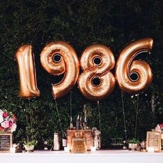 a table topped with gold balloons that spell out the number nineteen sixty ninety eighty nine