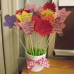 a vase filled with lots of paper flowers on top of a wooden table next to a door