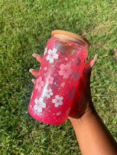 a hand holding a pink and white flowered drink in it's left arm