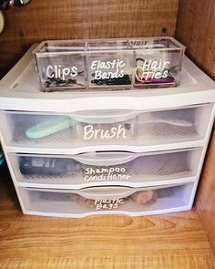 three clear drawers with labels on them in a bathroom cabinet next to toiletries and other items