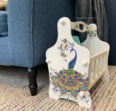 a baby crib with a peacock painted on the front and sides, next to a blue couch