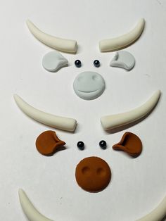 an animal's face made out of white and brown clay with eyes, nose, and teeth