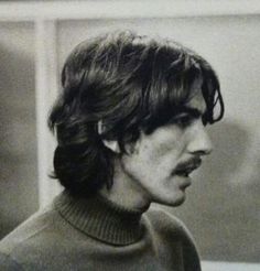 black and white photograph of a man with moustache on his face, wearing a turtle neck sweater