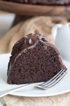 a piece of chocolate cake on a white plate with a fork in front of it