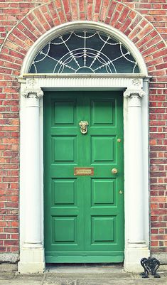 a green door in front of a brick building