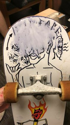 a skateboard with some drawings on it and someone's hand holding the board