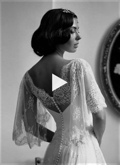 the back of a woman's wedding dress in front of a wall with a clock