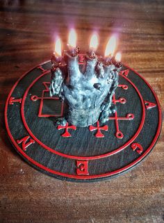 a metal candle holder with candles in it on top of a wooden table next to a clock