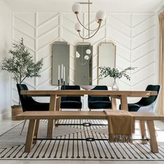 a dining room table with chairs and a bench in front of the mirror on the wall