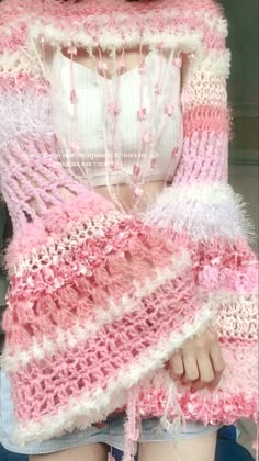 a woman wearing a pink and white crocheted shawl with fringes on it