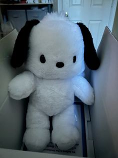 a white stuffed dog sitting in a box