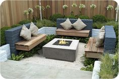 a fire pit surrounded by wooden benches and pillows