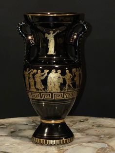 a black and gold vase sitting on top of a marble table