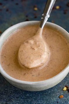 a spoon in a bowl filled with some kind of sauce on top of a table