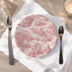 a pink and white plate sitting on top of a table next to two silverware