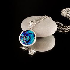 a necklace that is sitting on top of a rock and has a blue swirl in the middle