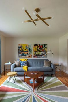 a living room filled with furniture next to a painting on the wall above a coffee table