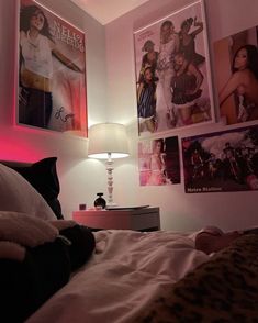 a bedroom with pink lighting and posters on the wall