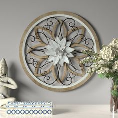 a white clock sitting on top of a wall next to a vase filled with flowers