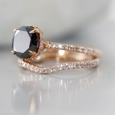 a black and white diamond engagement ring set on top of a table with diamonds around it