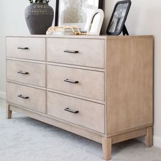 a dresser with several drawers and pictures on it's top, next to a framed photograph