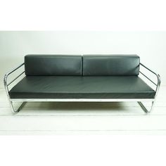 a black leather couch sitting on top of a metal frame sofa bed with armrests