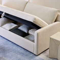 a couch that has some pillows on it and is open to show the contents inside