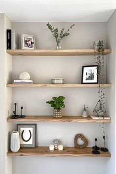 three wooden shelves with plants and pictures on them