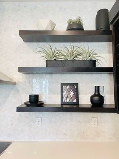 two black vases are sitting on some shelves