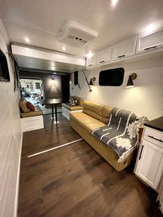 the interior of a recreational vehicle with wood floors and white cabinets, including a couch