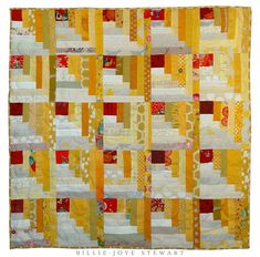 a yellow and red quilt is hanging on the wall