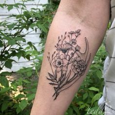 a black and white flower tattoo on the left arm, with flowers in it's center