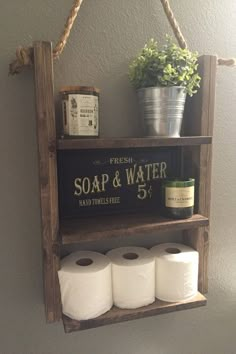 a wooden shelf with two rolls of toilet paper hanging from it's sides and a sign that says soap & water