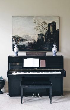 a black piano sitting in front of a painting